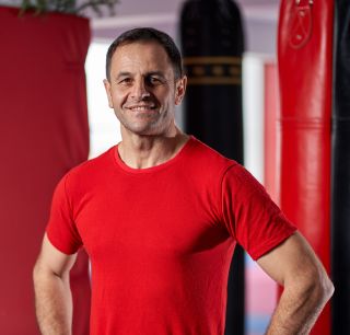 kickboxing coach posing his gym with punchbags background (1)